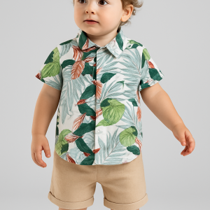 Toddler boy wearing a tropical leaf print button-up shirt and beige shorts.